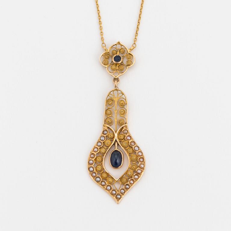 A necklace set with seed pearls, a cabochon cut sapphire, probably another sapphire and filigree work.