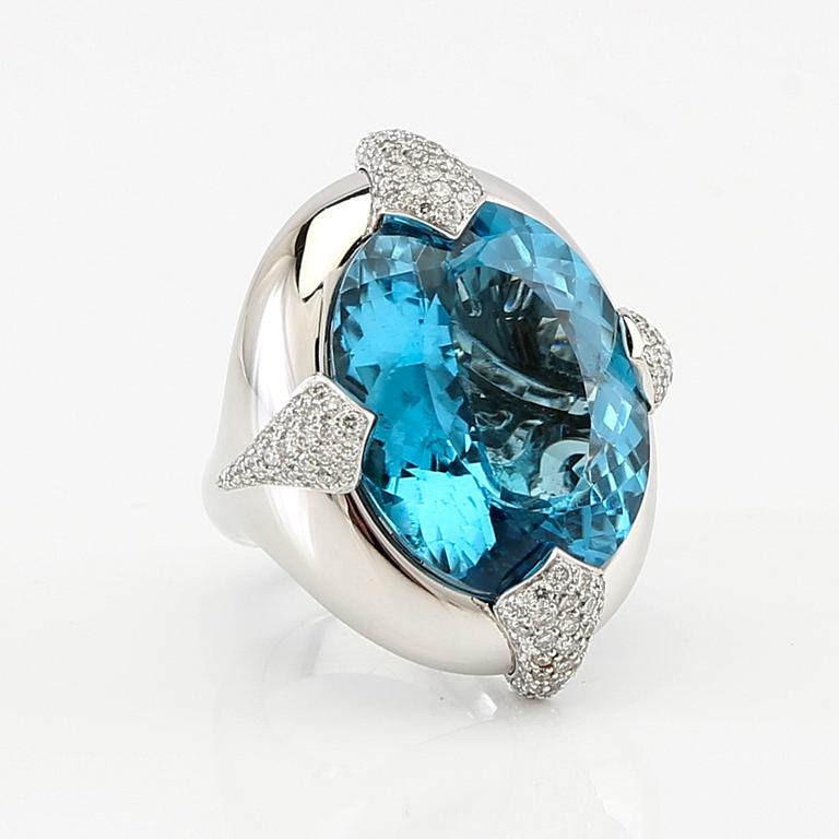 Pavé-set ring/cocktail ring in 18K white gold with an oval faceted blue topaz and round brilliant-cut diamonds.