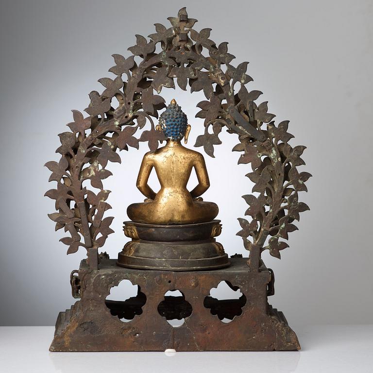 A large Nepalese gilt bronze buddha on a throne with mandorla, 18/19th Century.