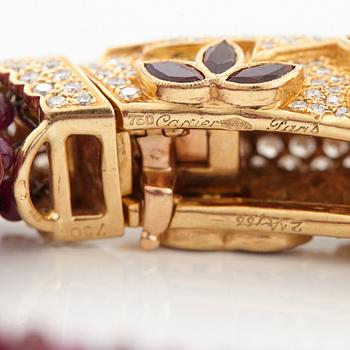 A Cartier chimera head bracelet in 18K gold set with round brilliant-cut diamonds and faceted rubies.