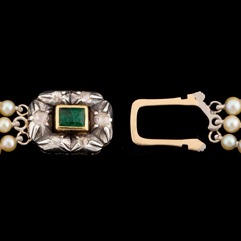 A three strand calibrated pearl necklace, clasp with emerald and diamonds.