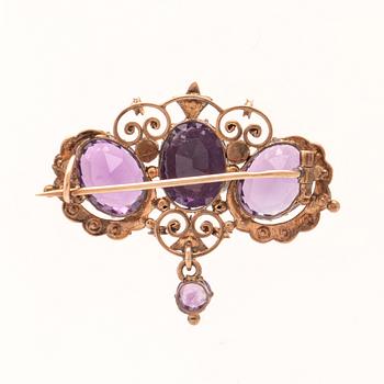An 8K gold brooch set with seed pearls and faceted amethysts.