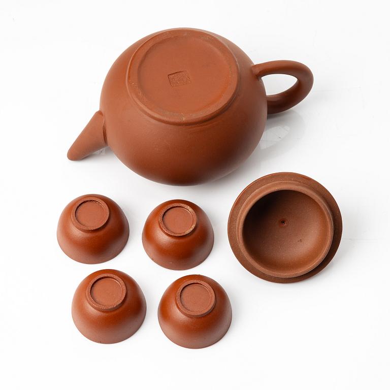 A six part red yixing Gongfu set; teapot, four cups and a tray, China, 1980s.