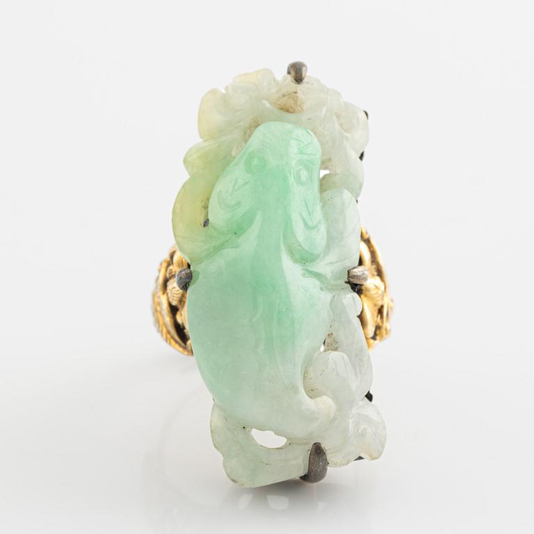 Ring in yellow metal with a white/green stone, possibly nephrite.".