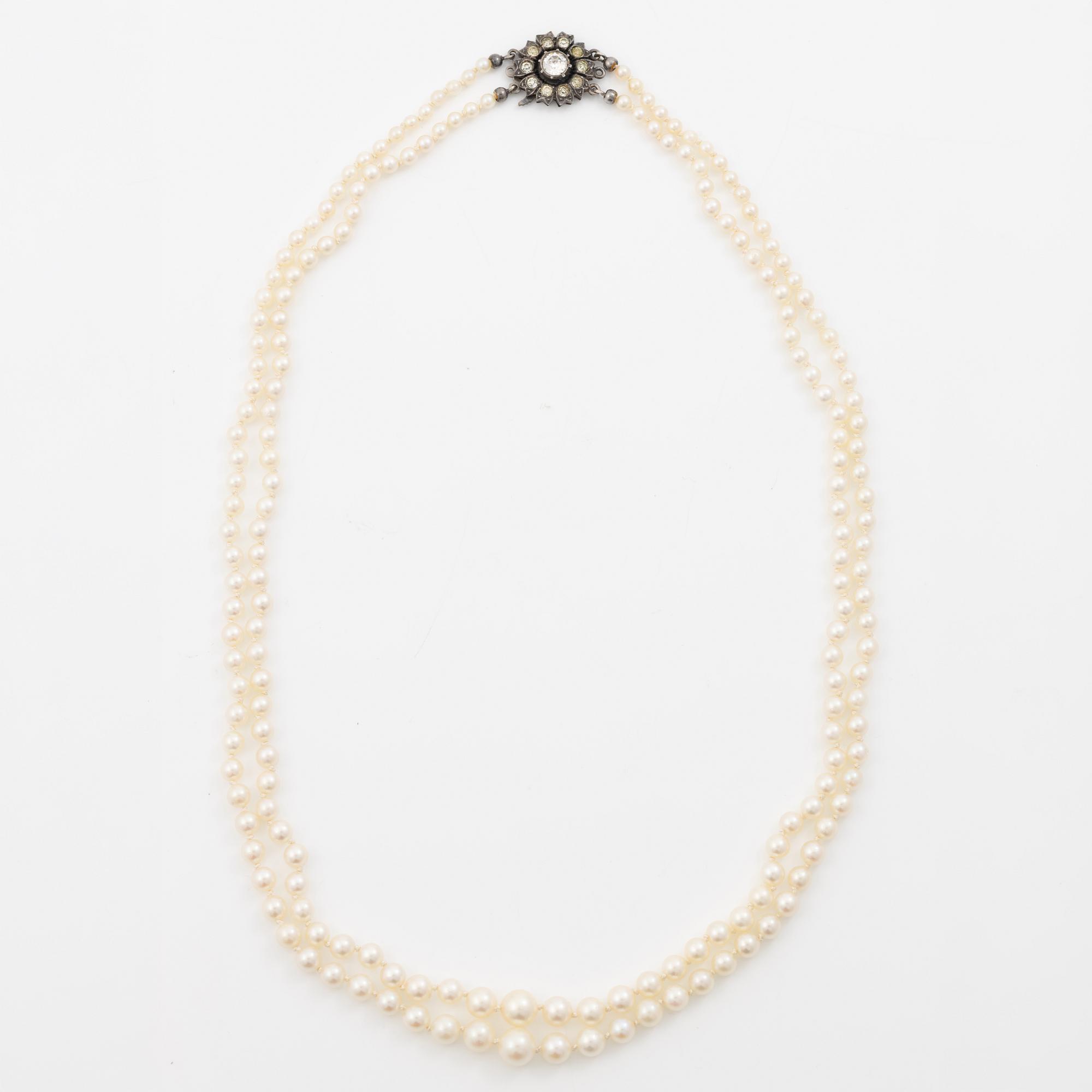 Double-row necklace with graduated cultured pearls, silver clasp set with paste stones.
