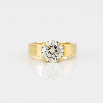 An 18K gold solitaire ring set with a round brilliant-cut diamond.