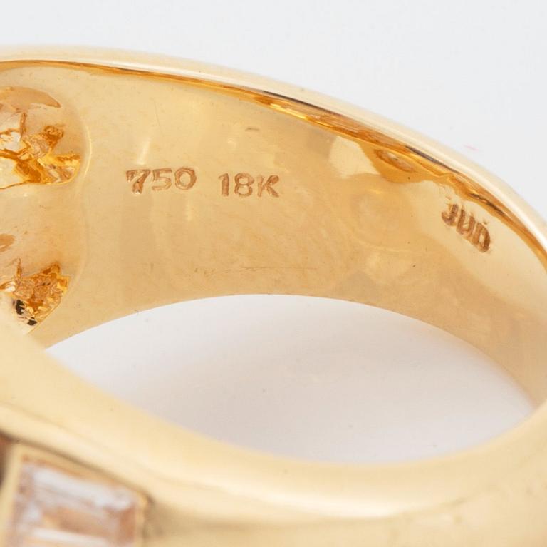 An 18K gold Junod ring set with a facted sapphire and tapered baguette-cut diamonds.