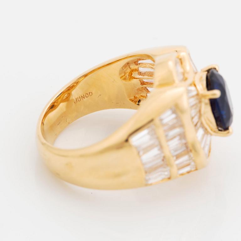 An 18K gold Junod ring set with a facted sapphire and tapered baguette-cut diamonds.