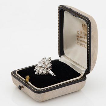 A platinum ring set with round brilliant-, navette- and baguette-cut diamonds.