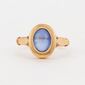 A ring set with a cabochon-cut, synthetic, blue spinel.