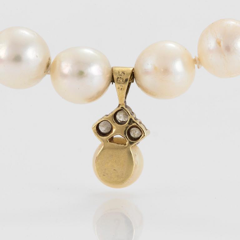 A necklace of cultured pearls with a pendant set with round, brilliant-cut diamonds and a silver clasp.