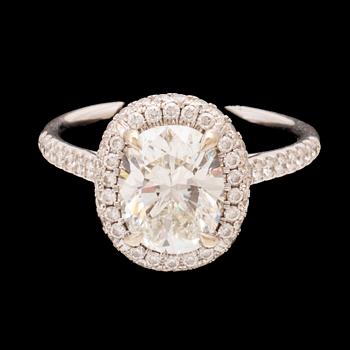 An 18K white gold ring by James Allen, set with an oval brilliant cut diamond in a halo of round brilliant cut diamonds.