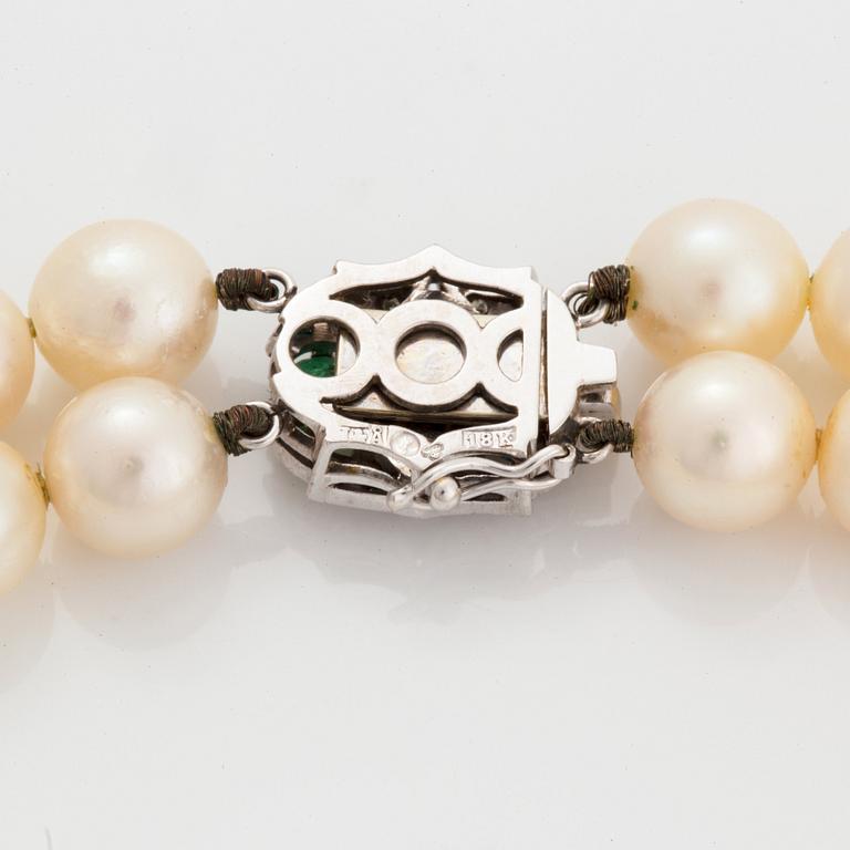 A two strand cultured pearl necklace clasp in 18K white gold set with a faceted emerald.