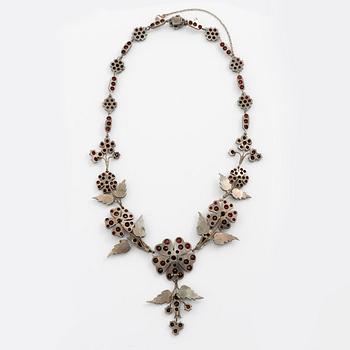 Garniture, necklace/bracelet and earrings in silver with garnets in the form of floral motifs, around the turn of the 20th century.