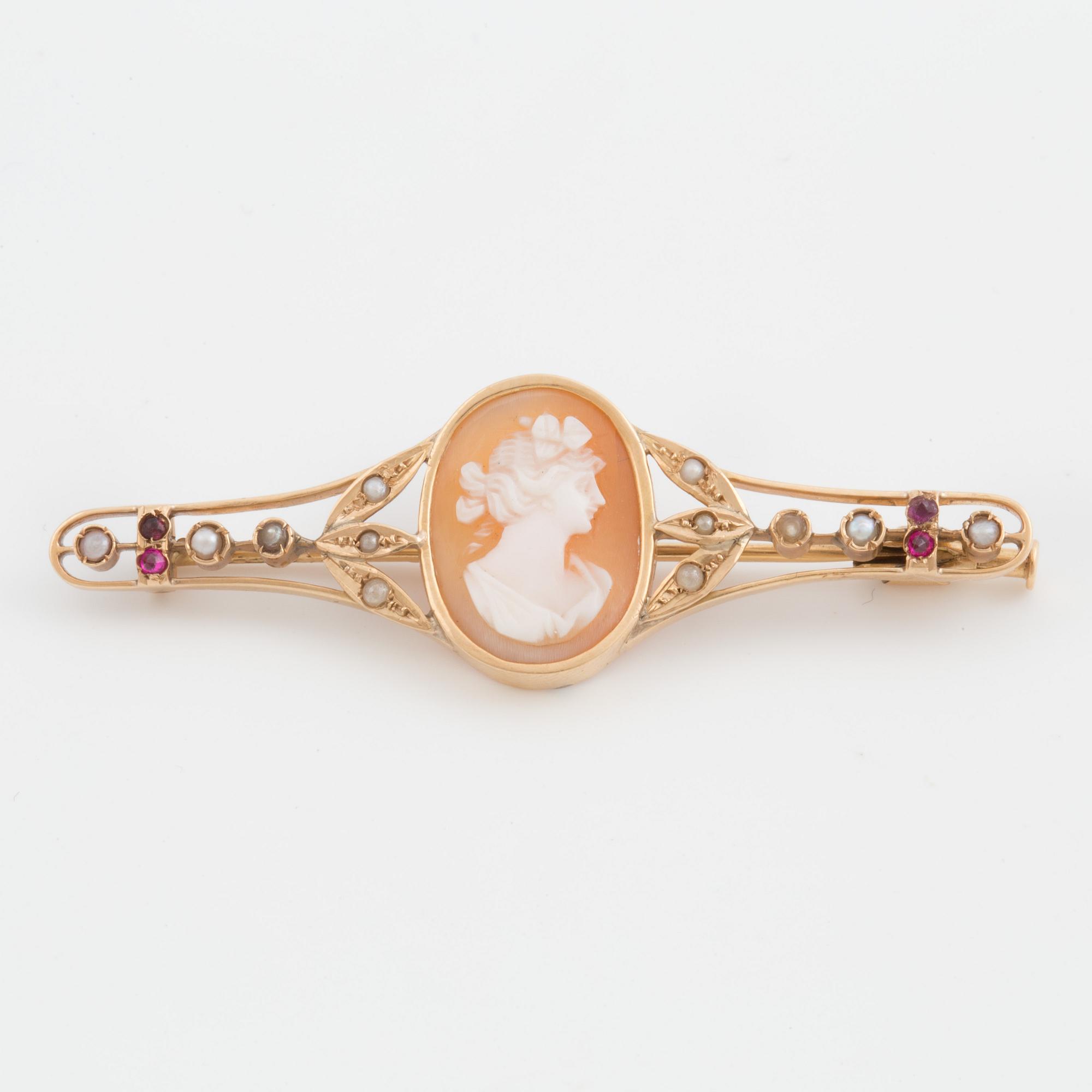 A brooch set with a shell cameo, seed pearls and probably synthetic rubies.