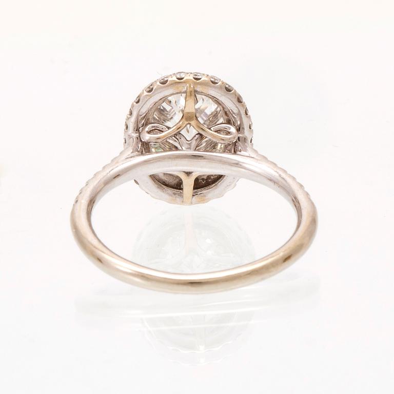An 18K white gold ring by James Allen, set with an oval brilliant cut diamond in a halo of round brilliant cut diamonds.