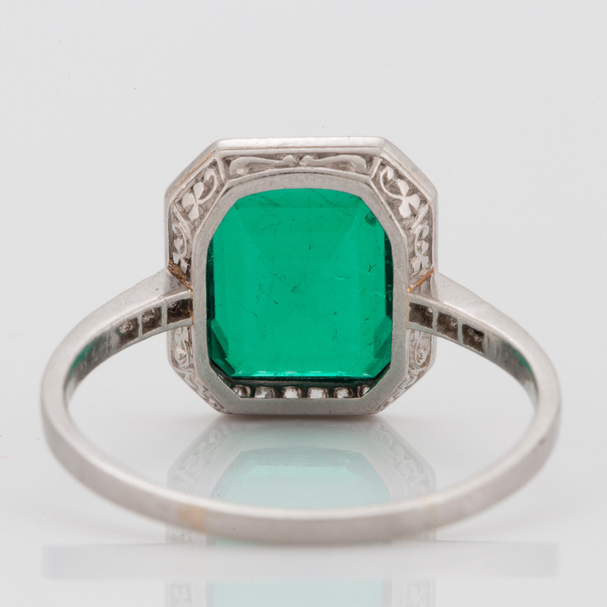 A platinum ring set with a Colombian step-cut emerald and old-cut diamonds in a fitted case from Cartier.