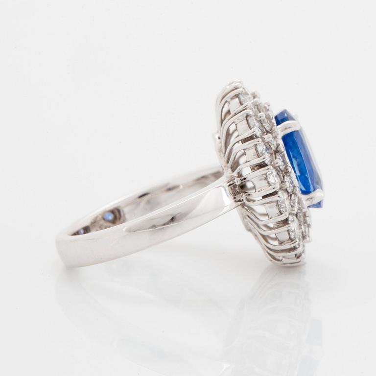 An 18K white gold ring set with an oval faceted sapphire and round brilliant-cut diamonds.