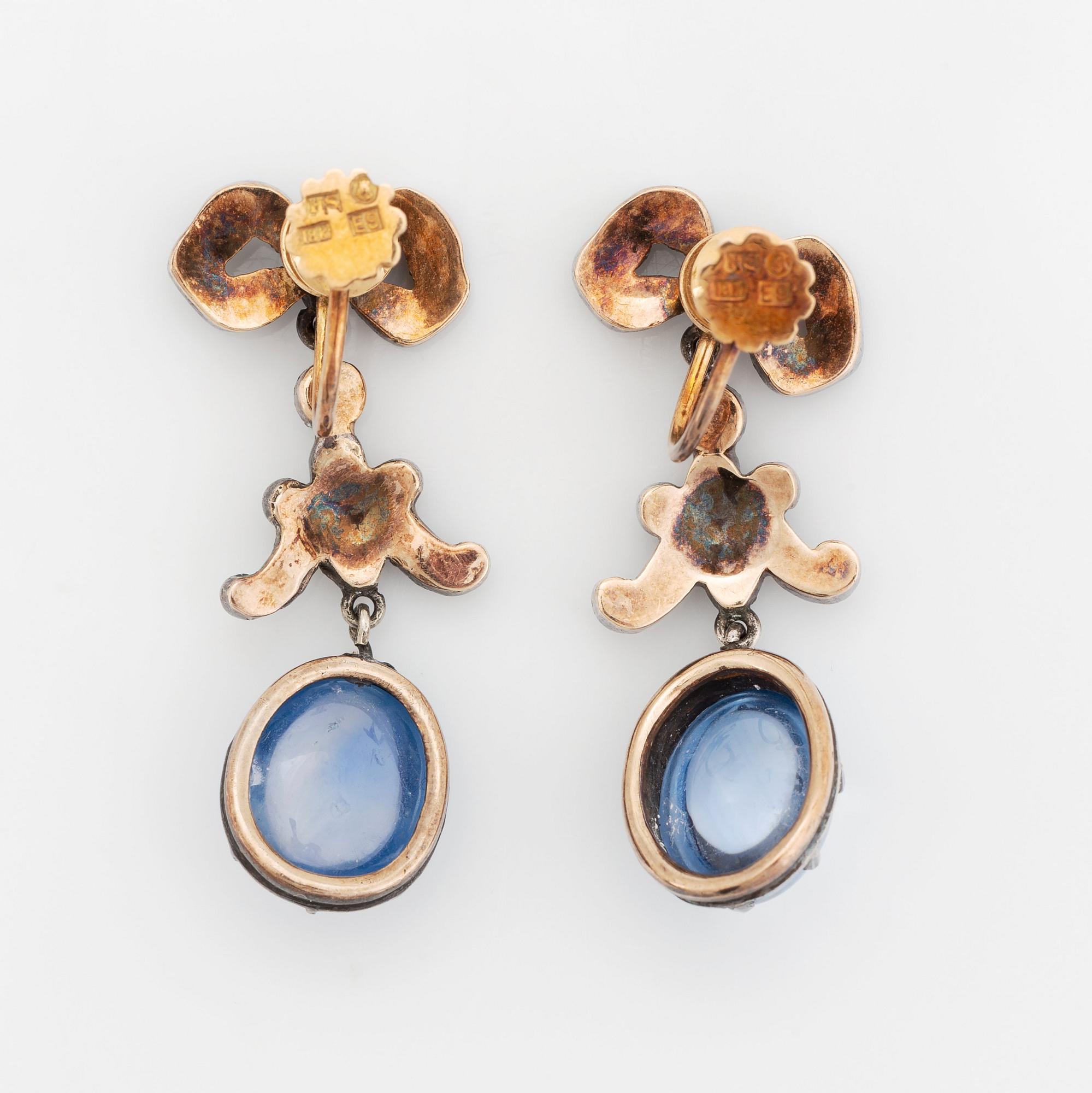 A pair of gold and silver earrings set with cabochon-cut sapphires and rose-cut diamonds.