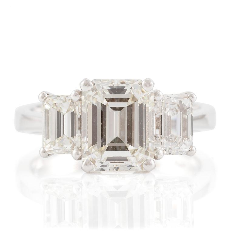 An 18K white gold ring set with three emerald-cut diamonds.