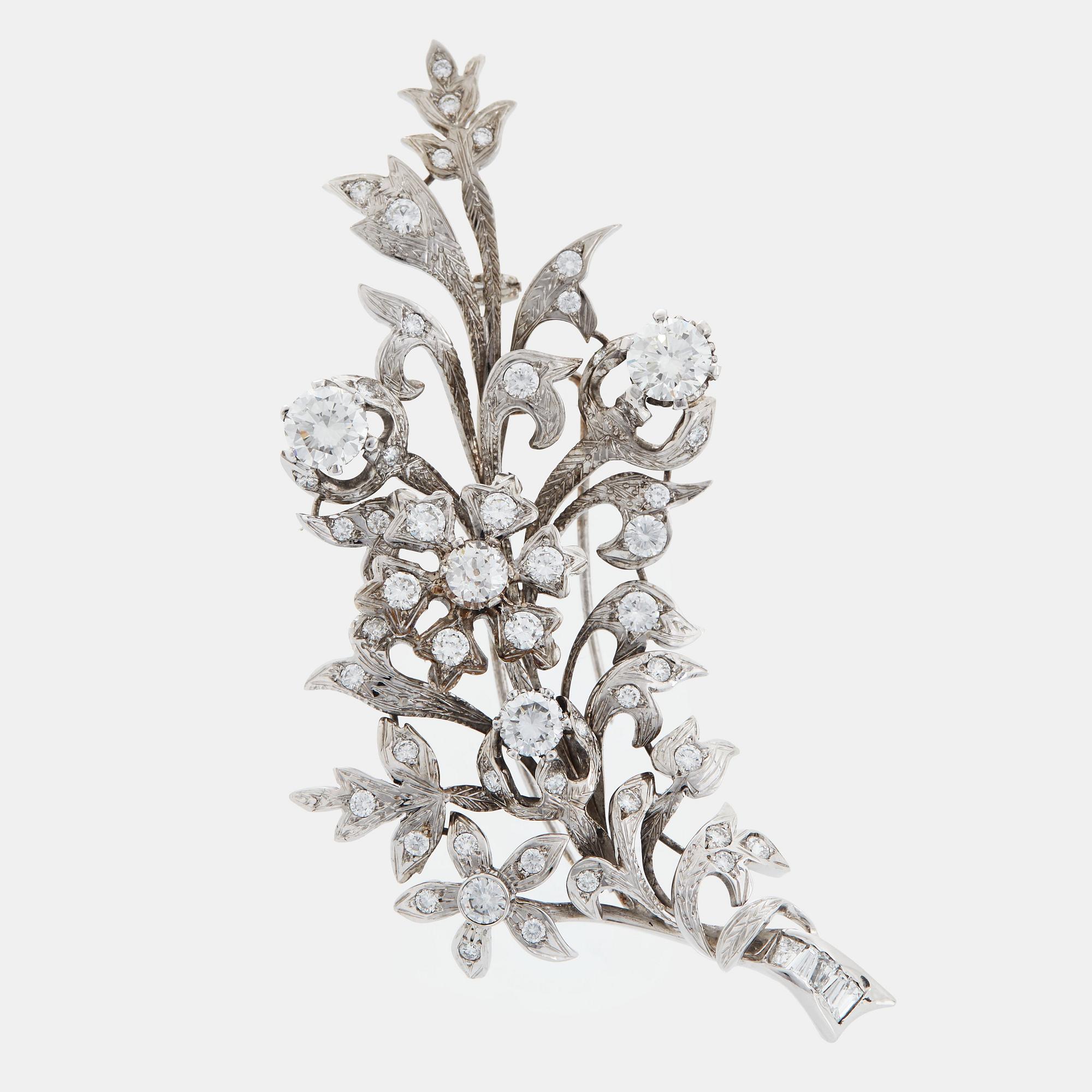 An 18K white gold brooch set with round brilliant-cut diamonds.