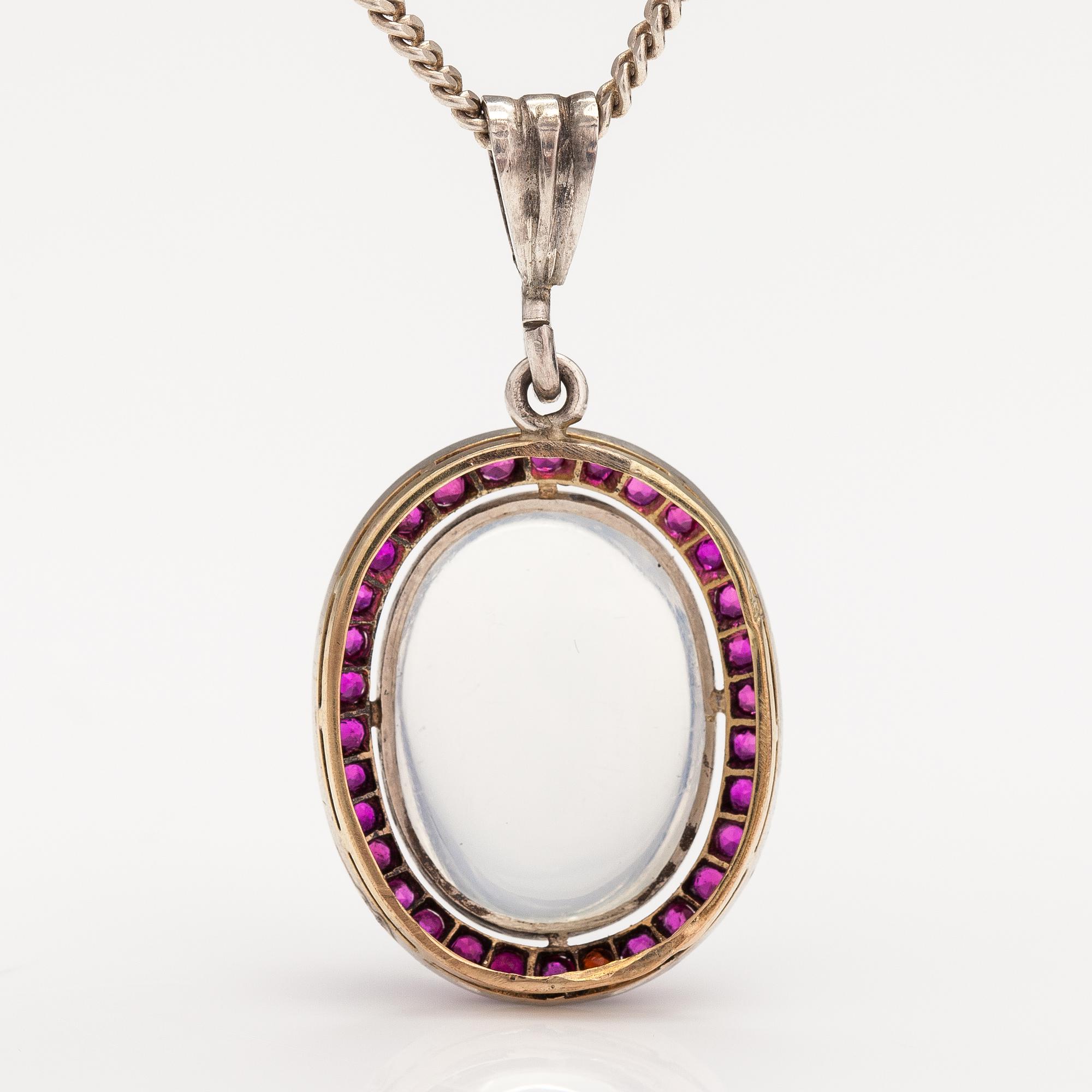 A 14K gold and silver necklace with a moon stone, rubies and a red glass stone.