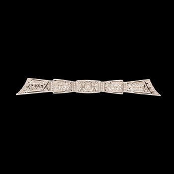 An 18K white gold brooch set with a round brilliant-cut diamond and rose-cut diamonds.