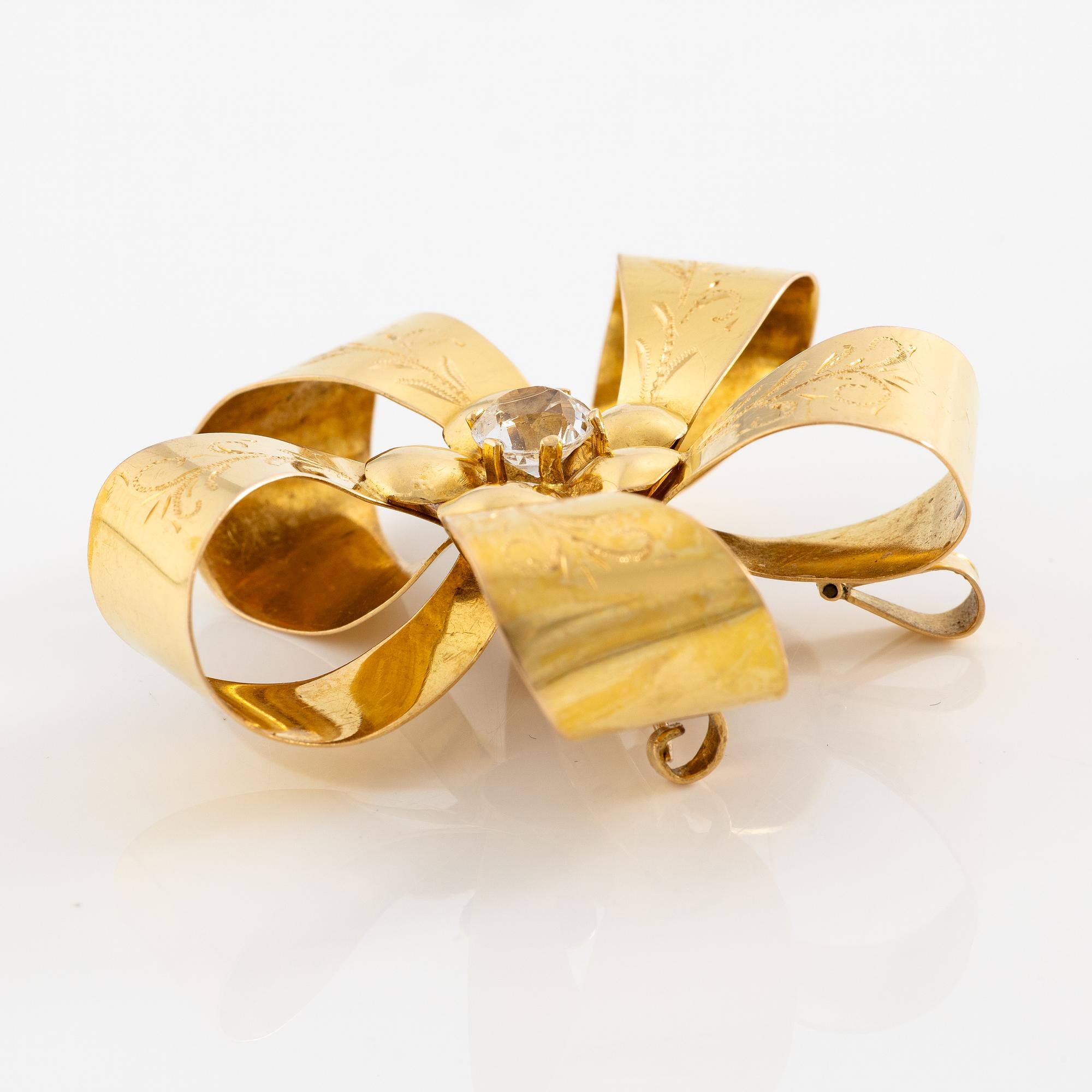 Brooch 18K gold with a white stone.