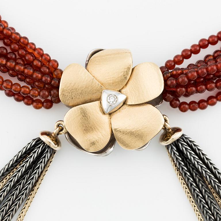 Ole Lynggaard, clasp in the shape of a flower, 18K gold with diamonds and two colliers, one in silver and gold with red stone beads.