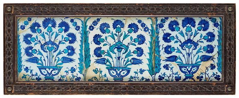 TILES, 3 pieces, glazed pottery. Iznik, Turkey, 17th century A.D. The mid tile 25,5 X 25,5 cm, the two others 24,5 X 24,5 cm each. Later wooden frame 33,5 x 84,5 cm.