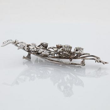 An 18K white gold brooch set with round brilliant-cut diamonds.