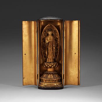 236. A Japanese gilt wooden figure of standing Buddha in a lacquer shrine, Meiji (1868-1912).