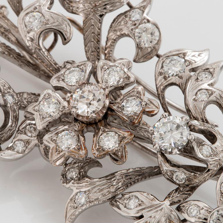 An 18K white gold brooch set with round brilliant-cut diamonds.