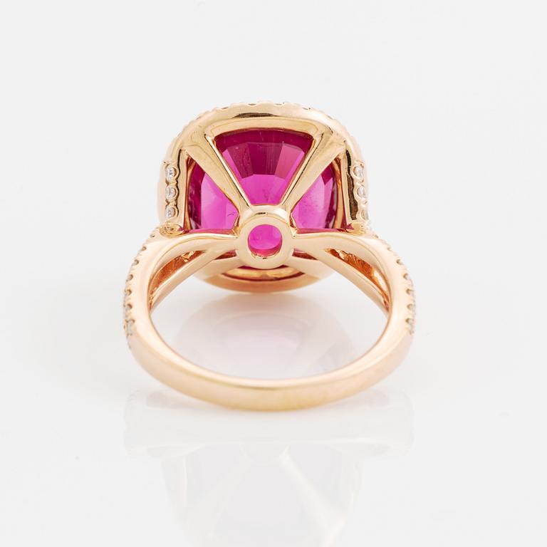 An 18K gold ring set with a faceted pink tourmaline and round brilliant-cut diamonds.