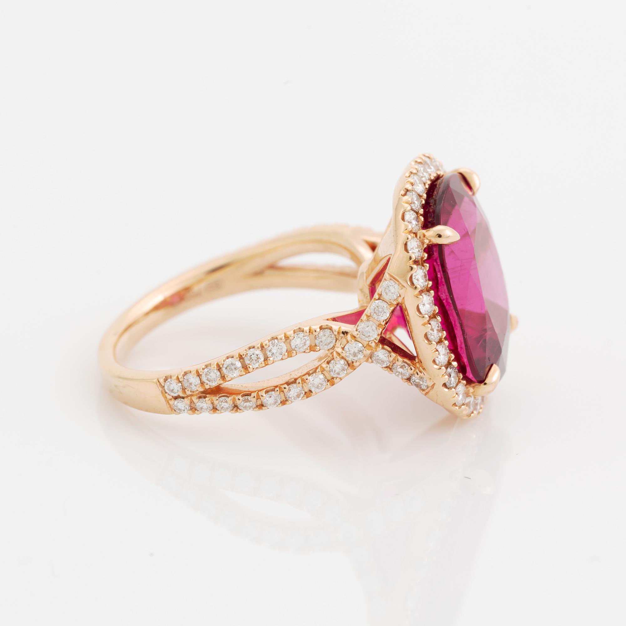 An 18K gold ring set with a faceted pink tourmaline and round brilliant-cut diamonds.
