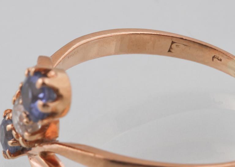 RING, 18K guld med äldre briljantslipad diamant samt 2 fasettslipade blå safirer.
