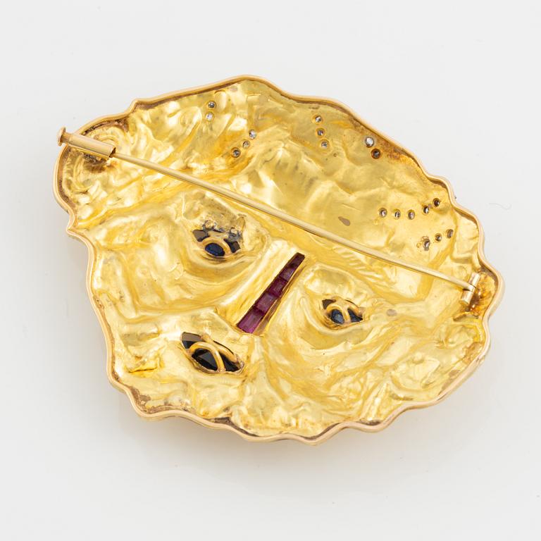 An 18K gold brooch set with diamonds and colored stones.
