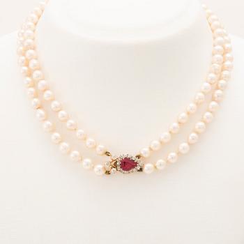 A double-stranded necklace with cultured pearls and an 18K gold clasp with a faceted synthetic ruby and old-cut diamonds.