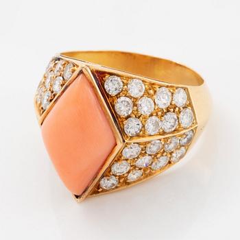 An 18K gold and coral ring set with round brilliant-cut diamonds.