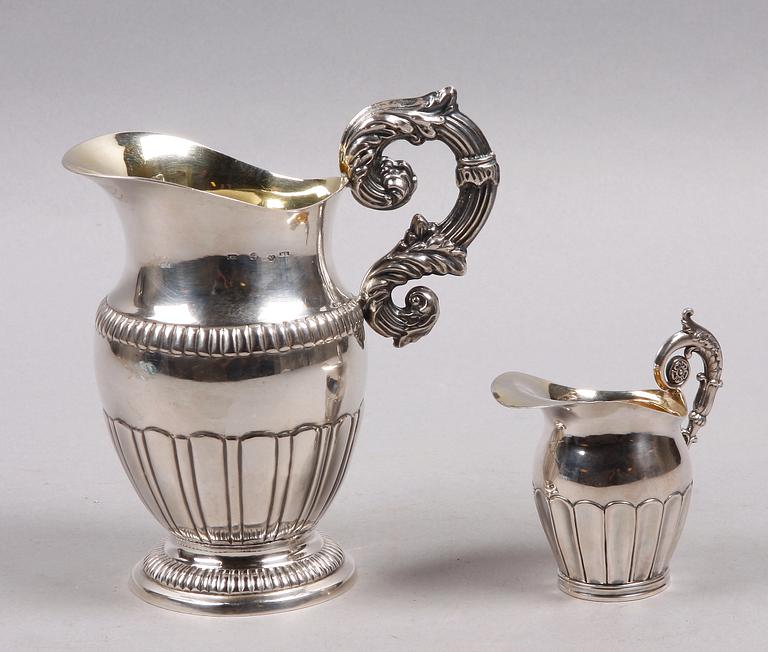 MJÖLK- RESP GRÄDDKANNA, 2 st, empire, Mattias Helén, Västervik resp Gustaf Folcker, Stockholm. 1845 resp 1844.