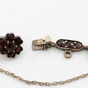 Garniture, necklace/bracelet and earrings in silver with garnets in the form of floral motifs, around the turn of the 20th century.