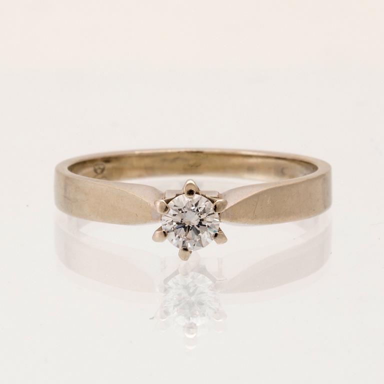 An 18K white gold solitaire ring set with a round brilliant-cut diamond.