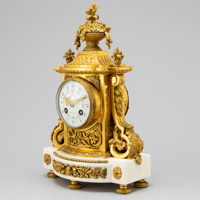 A late 19th century pendulum clock and a pair of candelabras.