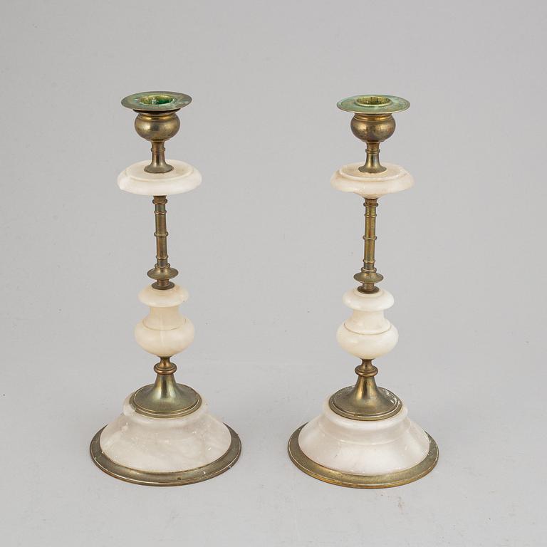 An alabaster mantle clock and pair of candlesticks, circa 1900.