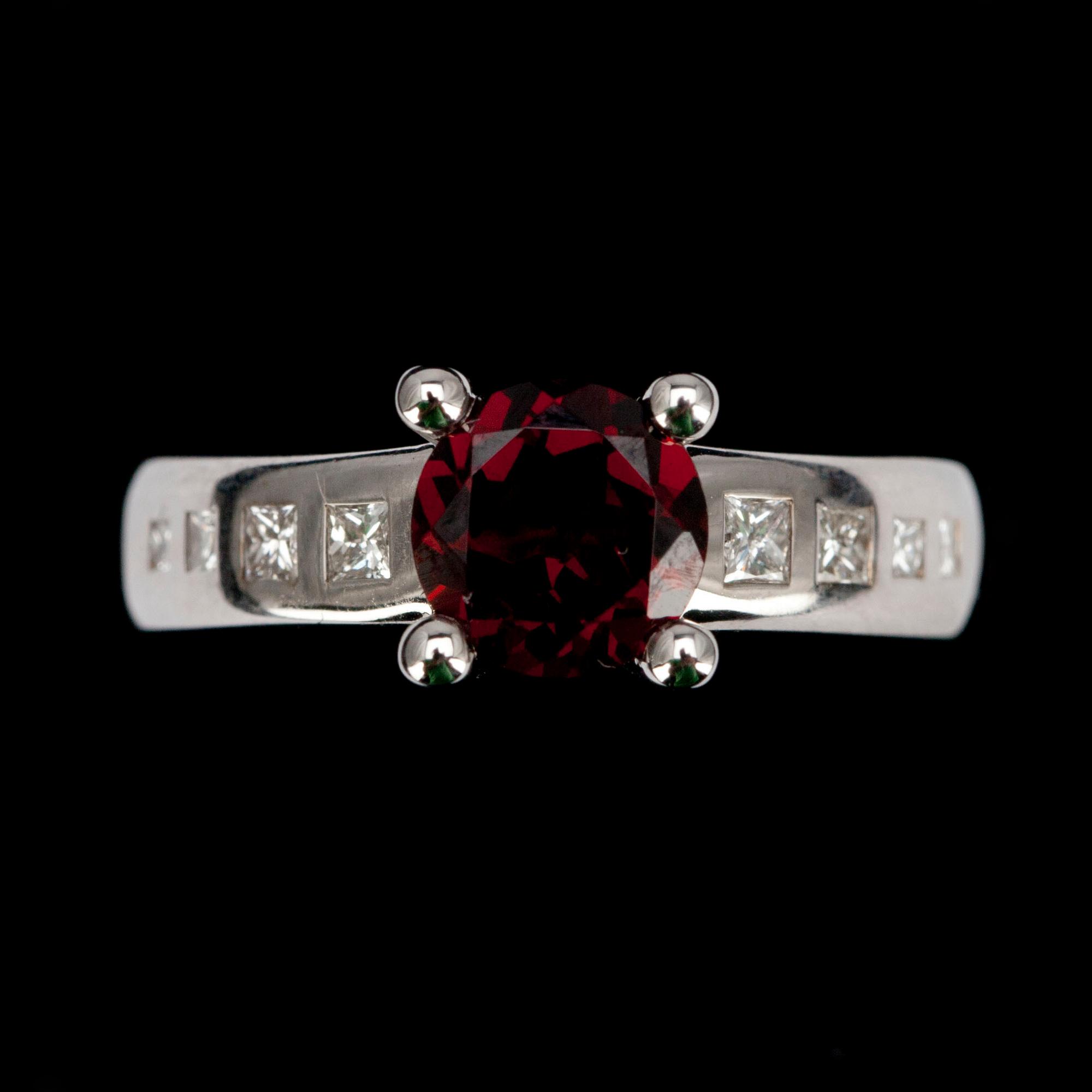 RING, vitguld 14K, med granat 1,58 ct samt 8 prinsesslipade diamanter tot. 0,28 ct. Vikt 5,4 g.