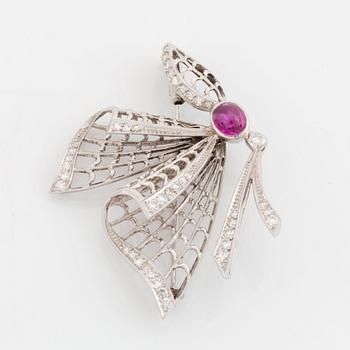 An 18K white gold brooch set with a cabochon-cut ruby and eight-cut diamonds.