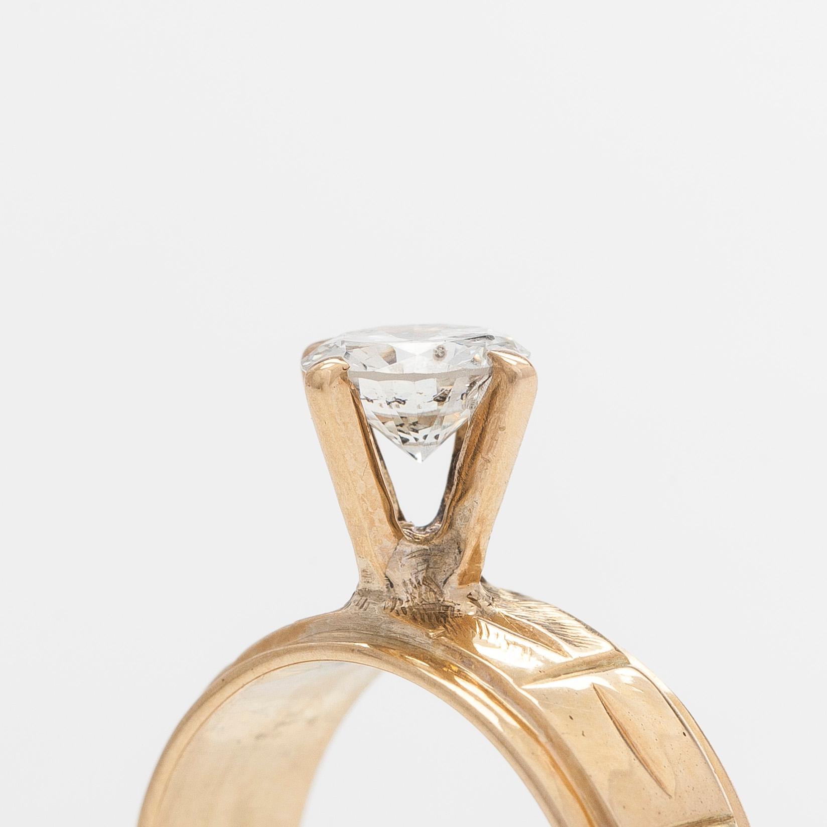 A 14K gold ring, set with a brilliant-cut diamond.