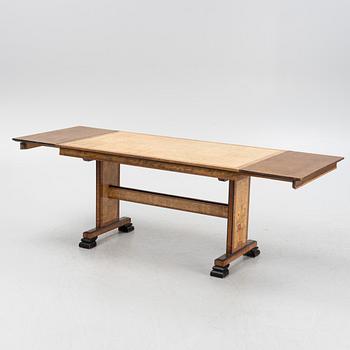 A 1930's birch and rosewood-veneered dining table.