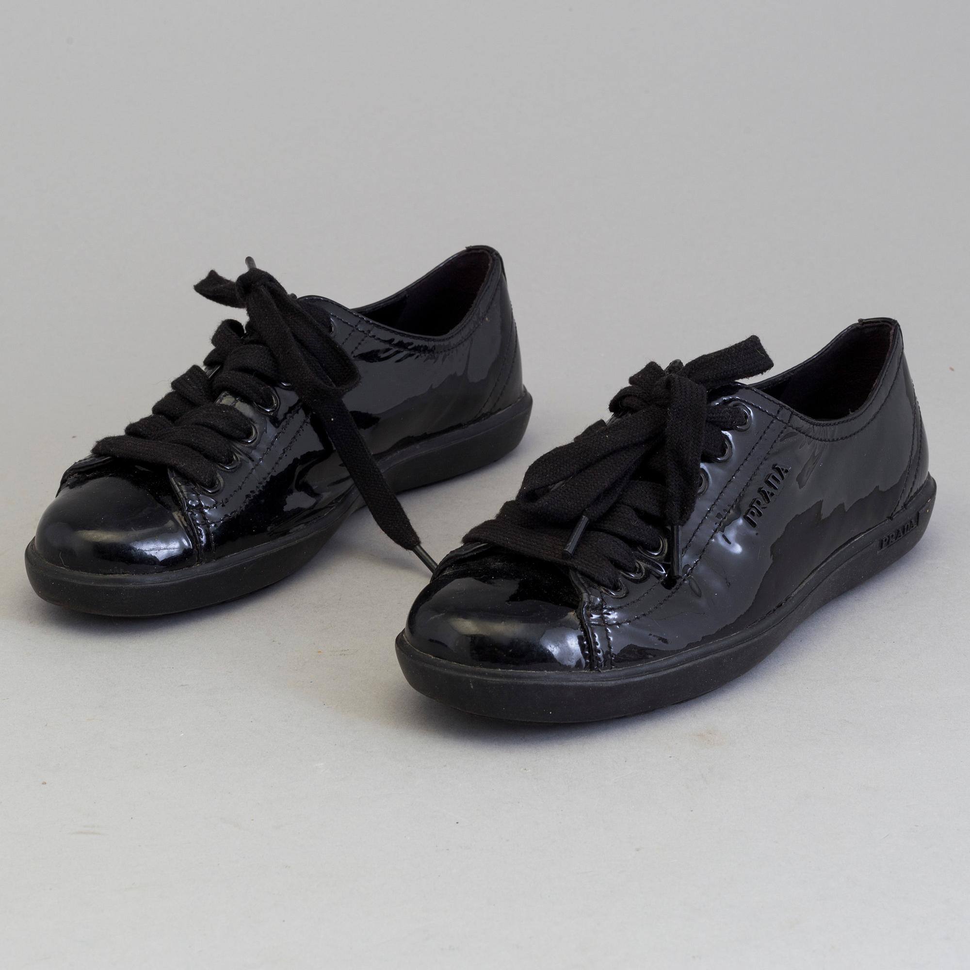 A pair of PRADA black patent leather sneakers.