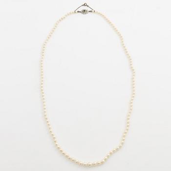 Necklace with graduated cultured pearls, with a clasp in 18K white gold set with an emerald.
